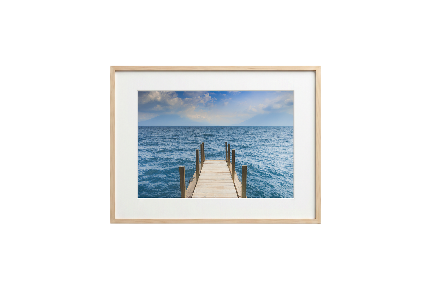 Framed photograph of a dock extending into the ocean on a white wall.