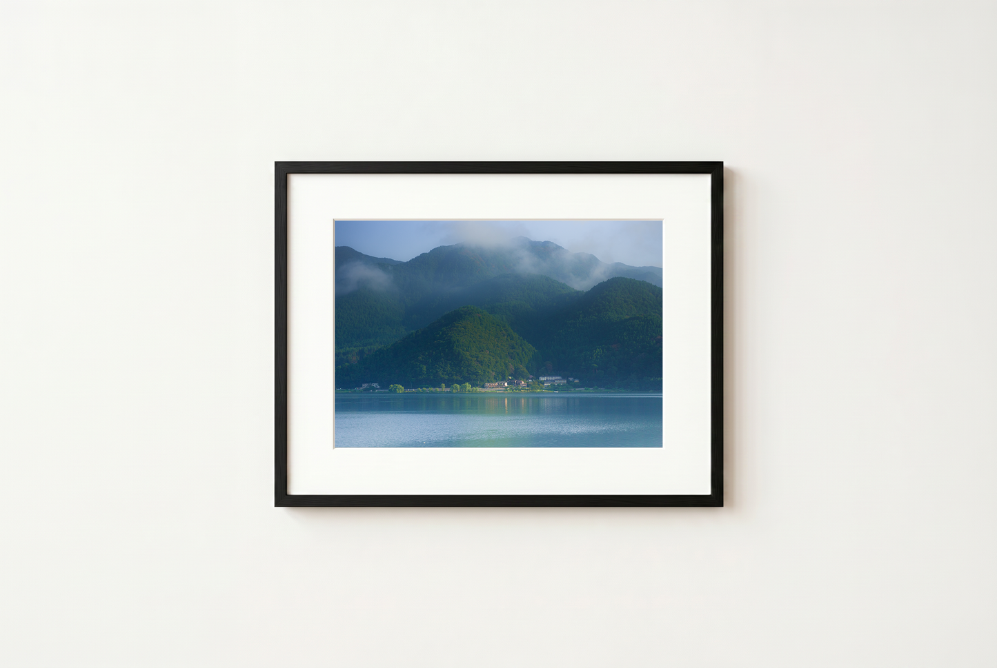 Framed photograph of a mountain landscape with a lake on a white wall