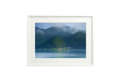 Framed artwork of a mountain landscape with a lake.