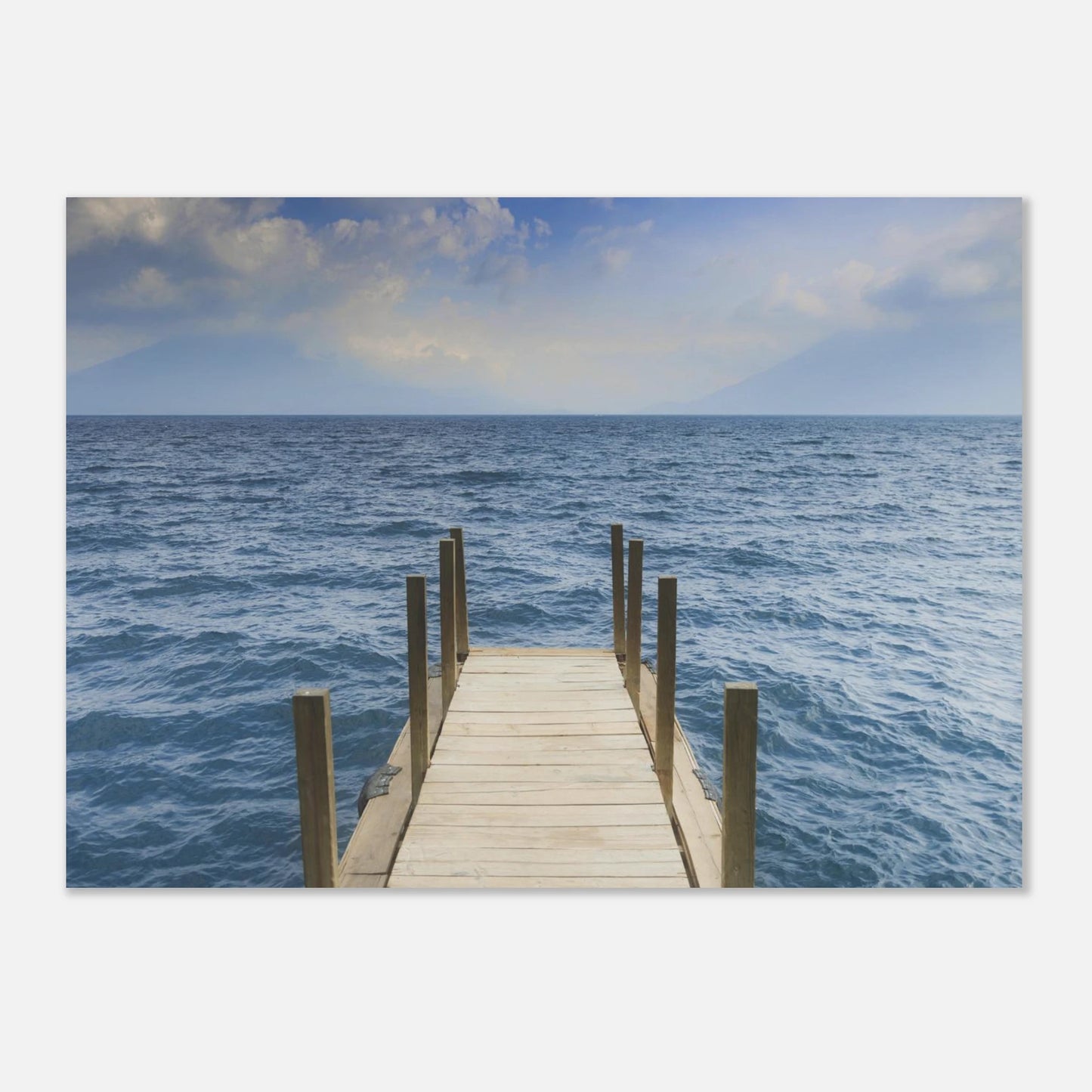 Framed photograph of a dock extending into the ocean on a white wall.