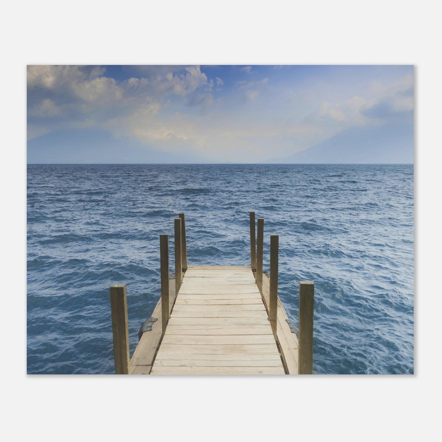 Framed photograph of a dock extending into the ocean on a white wall.