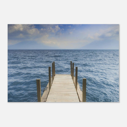 Framed photograph of a dock extending into the ocean on a white wall.