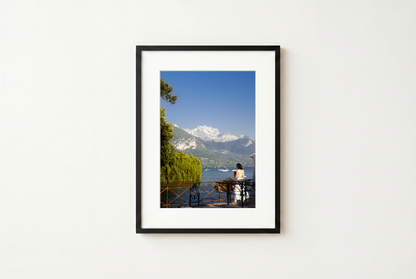 Framed photograph of a scenic view with mountains and a lake on a white wall.