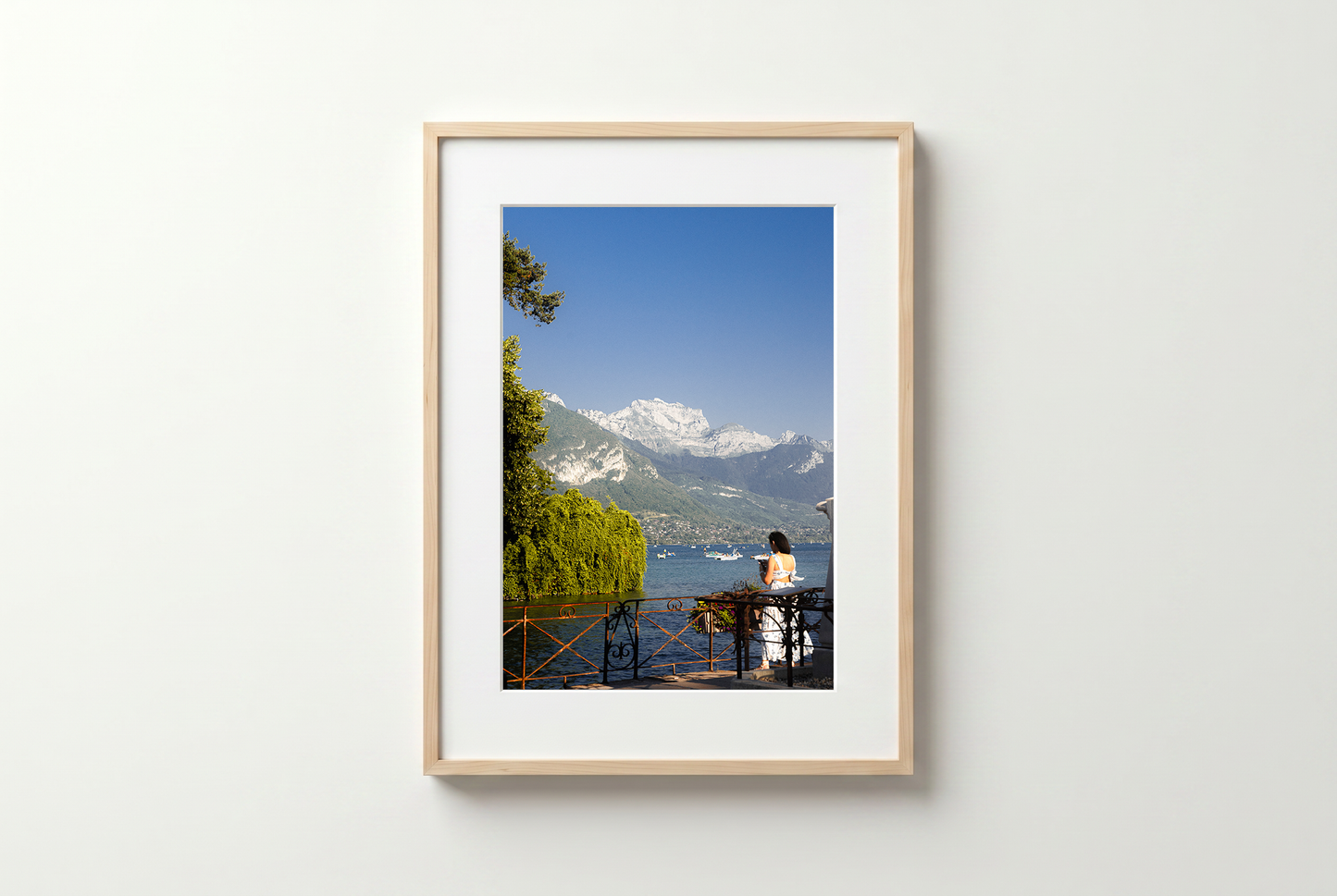 Framed photograph of a scenic view with mountains and a person sitting on a bench.