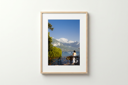 Framed photograph of a scenic view with mountains and a person sitting on a bench.