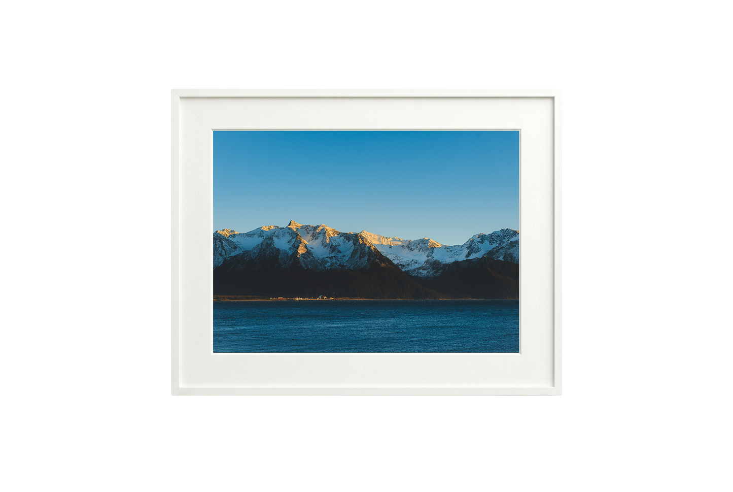 Framed picture of a mountain landscape with snow-capped peaks and a blue sky.
