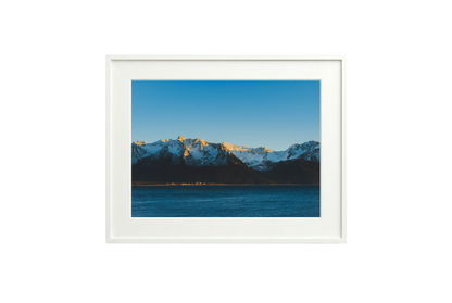 Framed picture of a mountain landscape with snow-capped peaks and a blue sky.