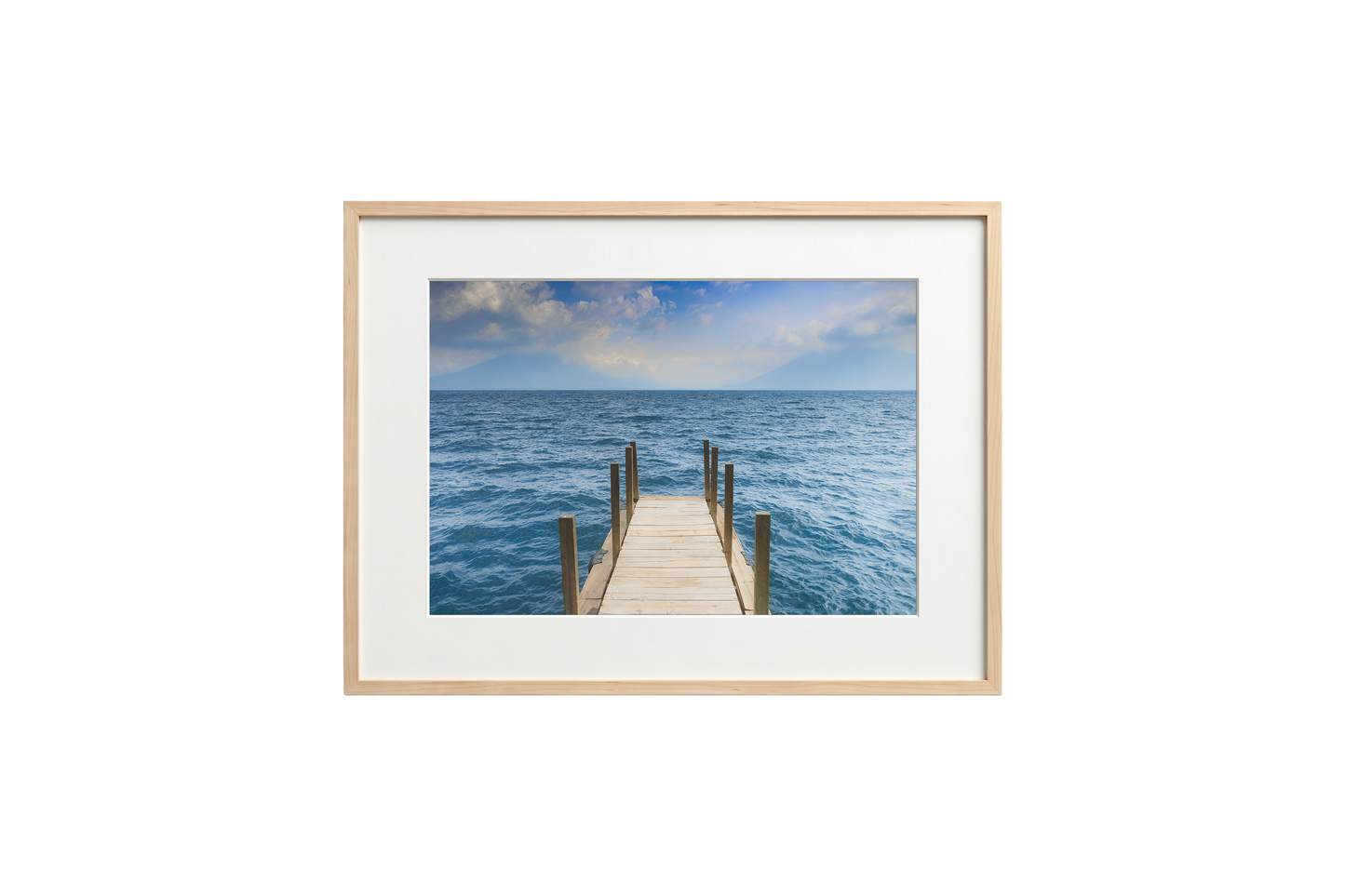 Framed photograph of a dock extending into the ocean on a white wall.