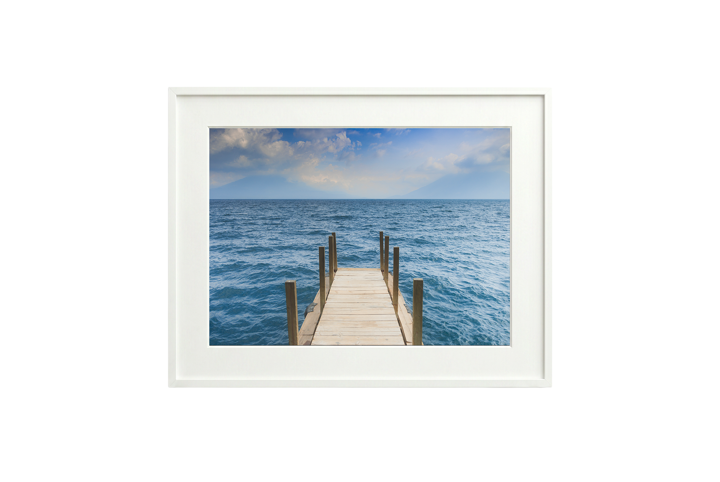 Framed photograph of a dock extending into the ocean on a white wall.