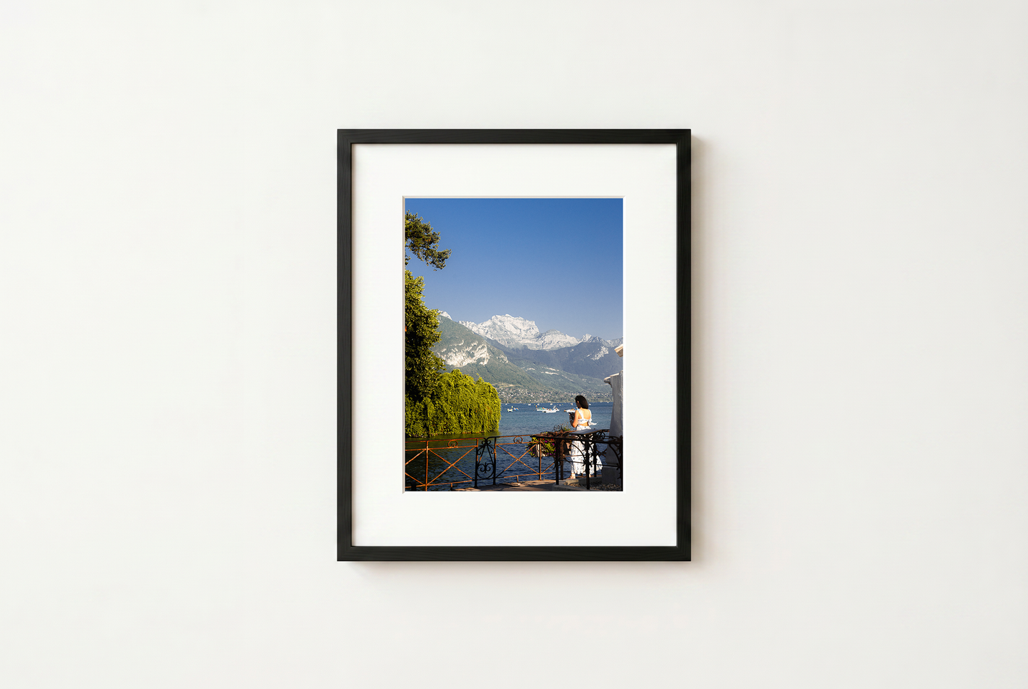 Framed photograph of a scenic view with mountains and a lake on a white wall.