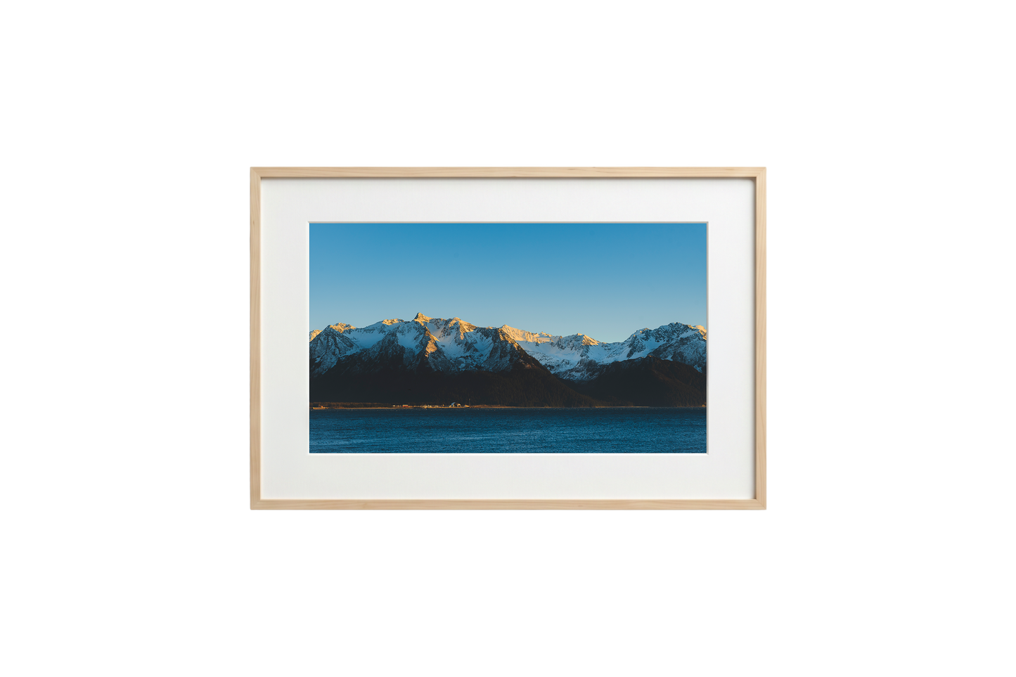 Framed photograph of a mountain landscape with snow-capped peaks and a clear blue sky.