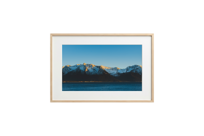 Framed photograph of a mountain landscape with snow-capped peaks and a clear blue sky.