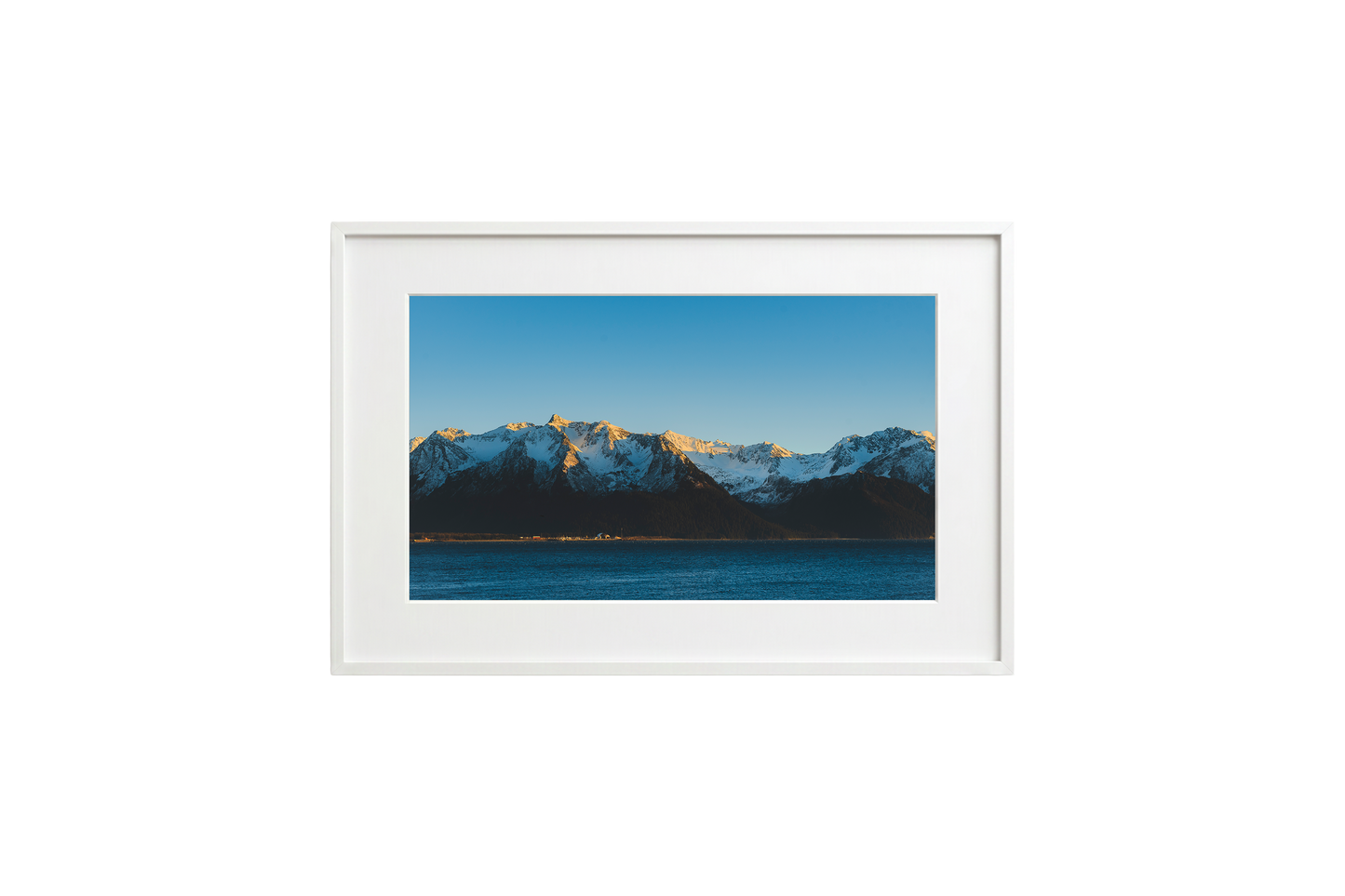 Framed picture of a mountain landscape with snow-capped peaks and a blue sky.