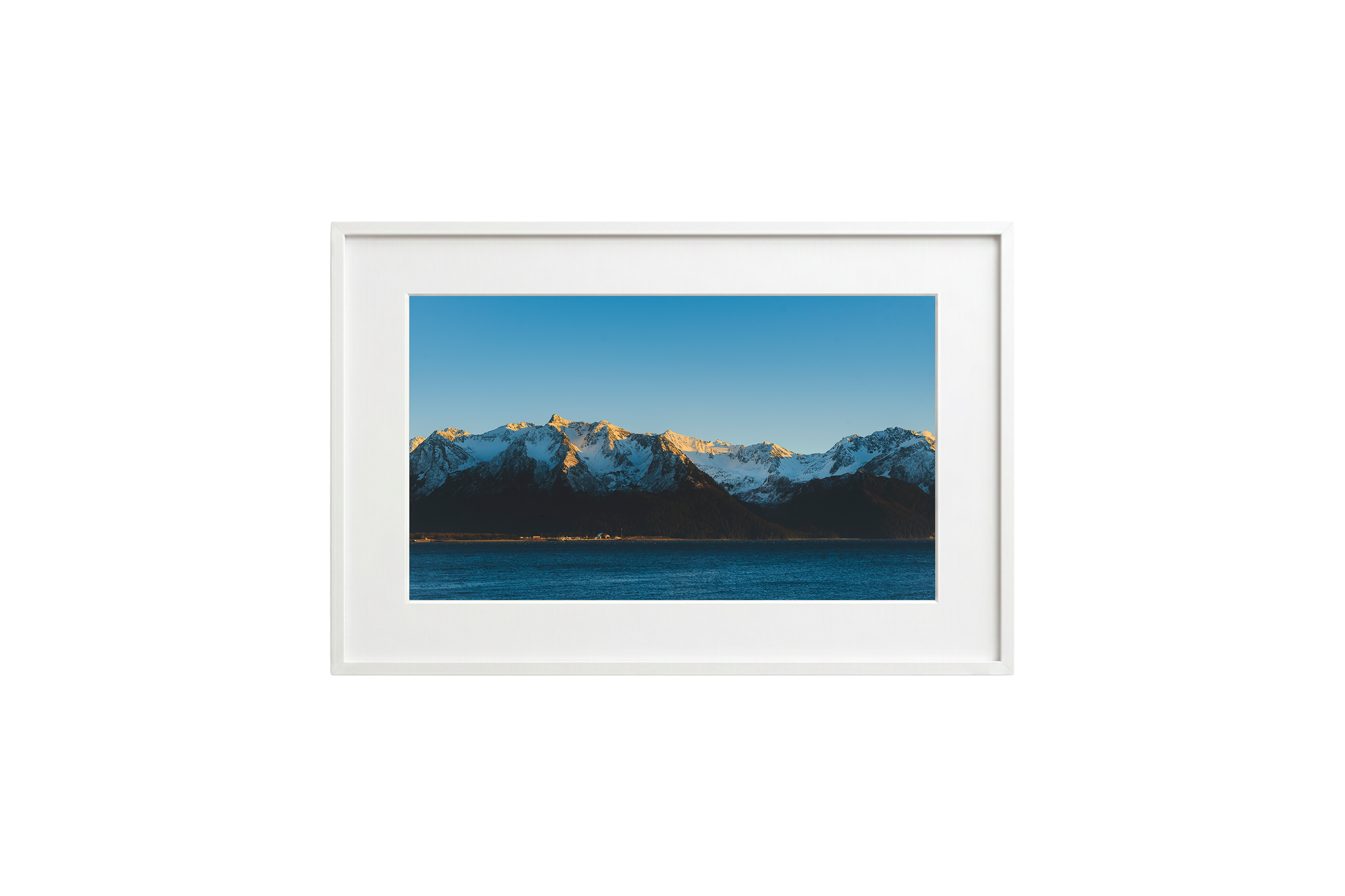 Framed picture of a mountain landscape with snow-capped peaks and a blue sky.