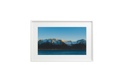 Framed picture of a mountain landscape with snow-capped peaks and a blue sky.