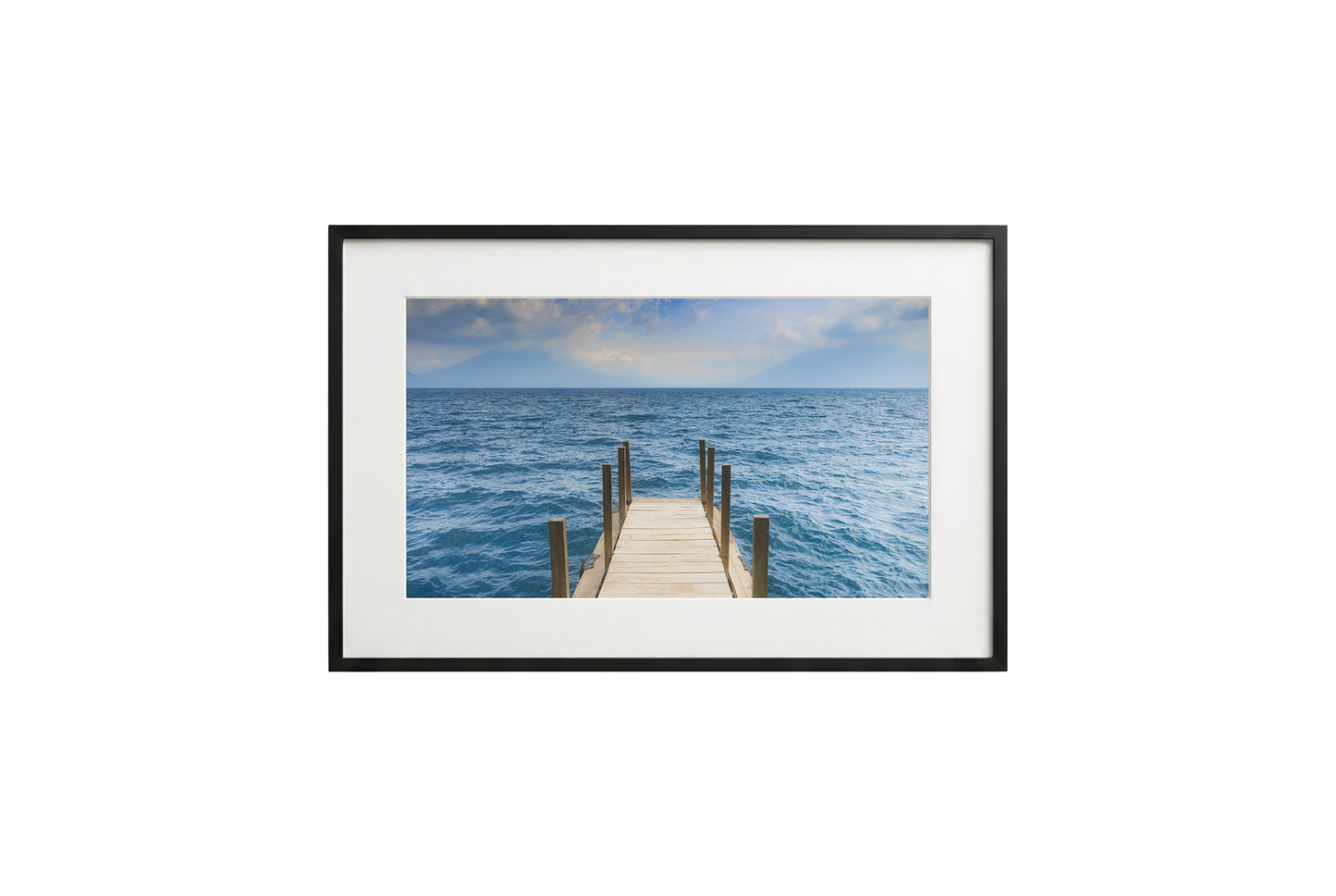 Framed photograph of a dock extending into the ocean on a white wall.