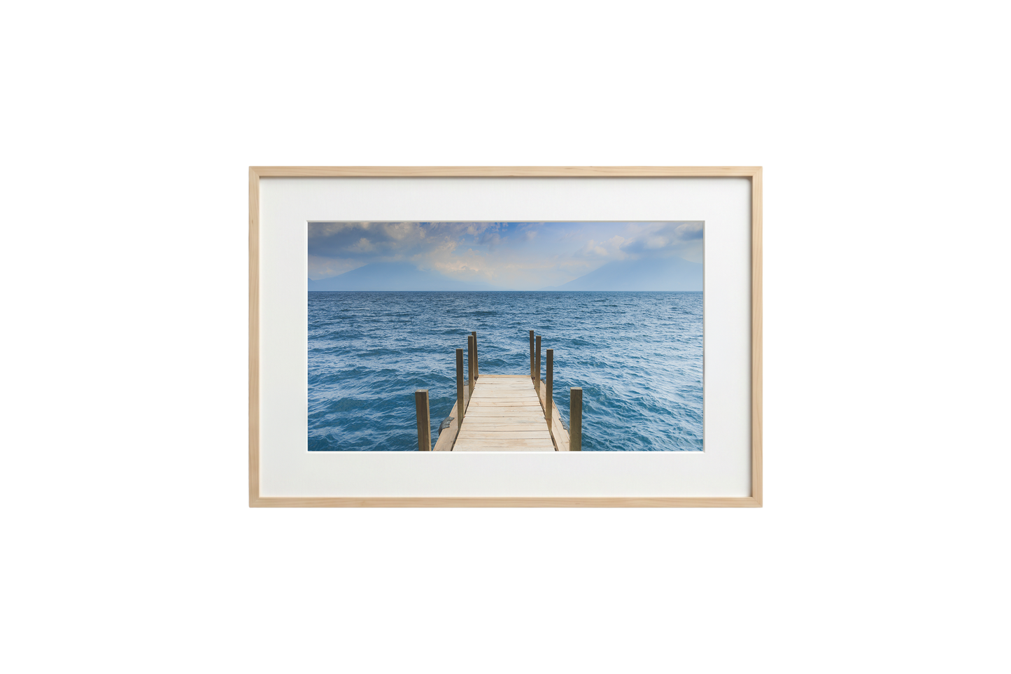 Framed photograph of a dock extending into the ocean on a white wall.