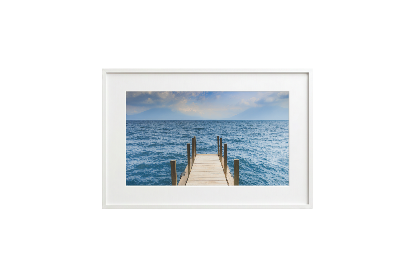 Framed photograph of a dock extending into the ocean on a white wall.