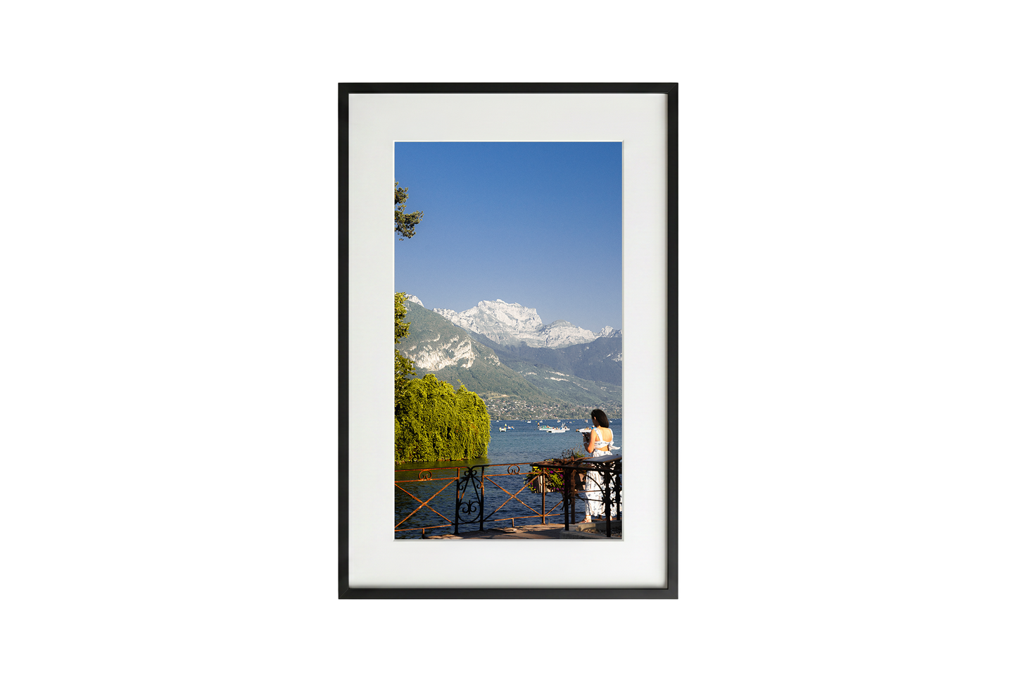 Framed artwork of a scenic view with mountains and a lake.