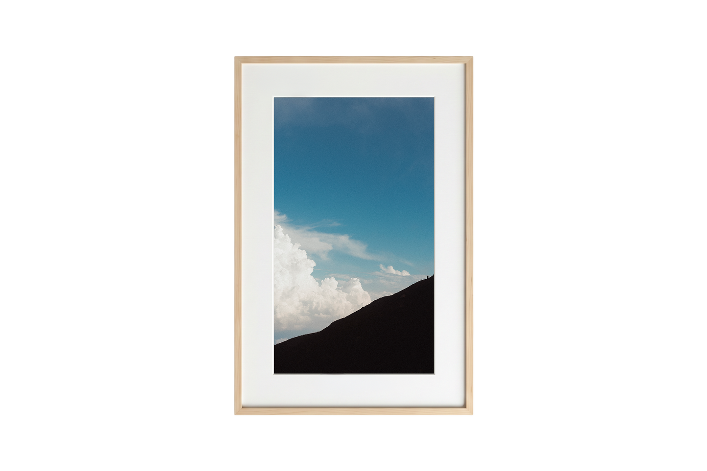 Framed photograph of a mountain landscape with blue sky and clouds.