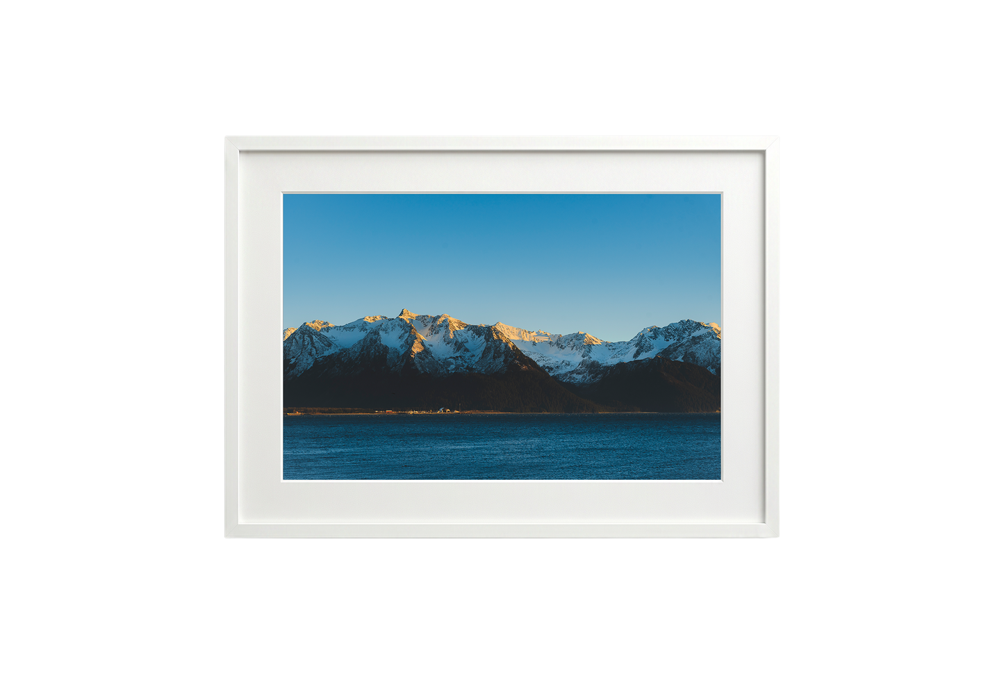 Framed photograph of a mountain range with snow and a blue sky.