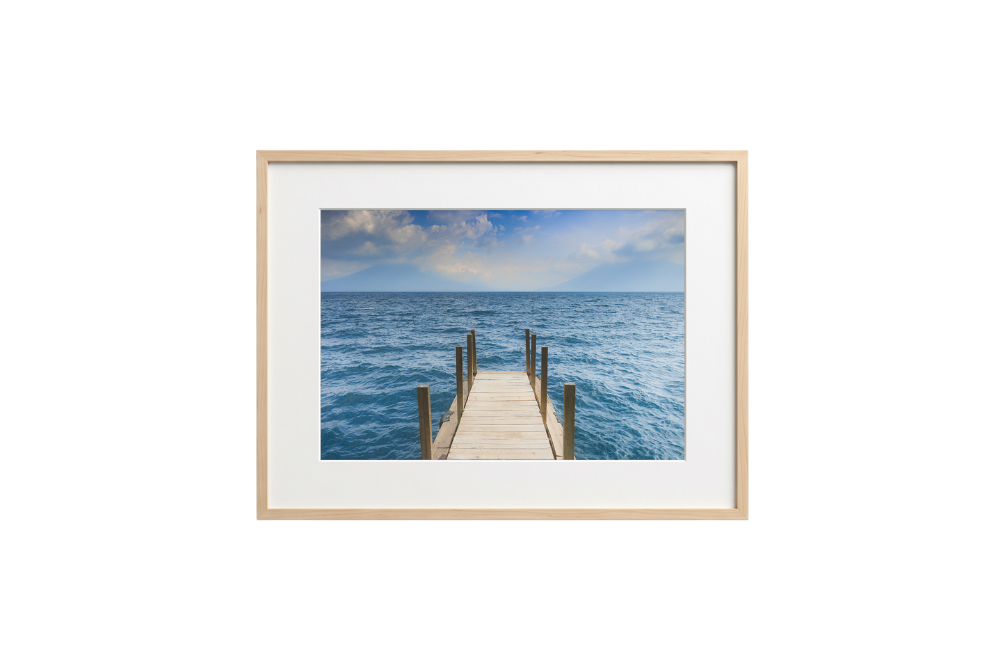 Framed photograph of a dock extending into the ocean on a white wall.