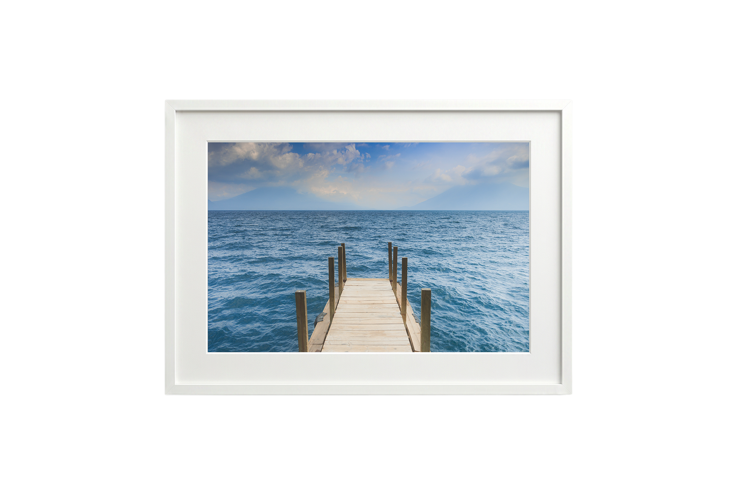 Framed photograph of a dock extending into the ocean on a white wall.