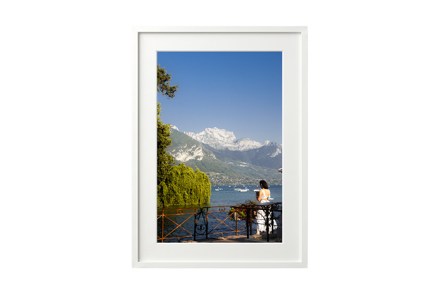 Framed photograph of a scenic view with mountains, water, and a person on a dock.