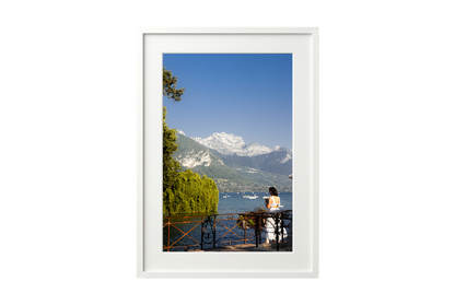 Framed photograph of a scenic view with mountains, water, and a person on a dock.