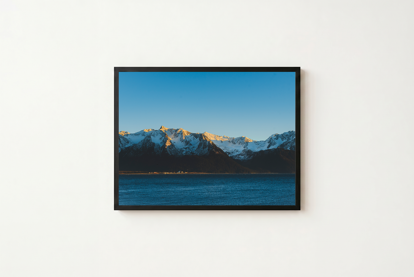 Framed photograph of a mountain landscape with a blue sky and water.
