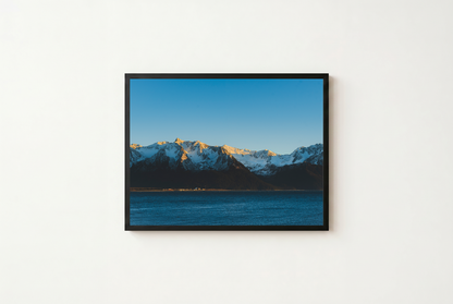 Framed photograph of a mountain landscape with a blue sky and water.