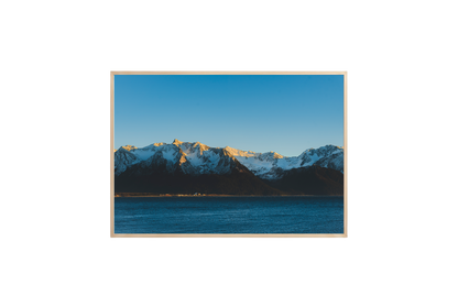 Framed photograph of a mountain range with snow and a blue sky.