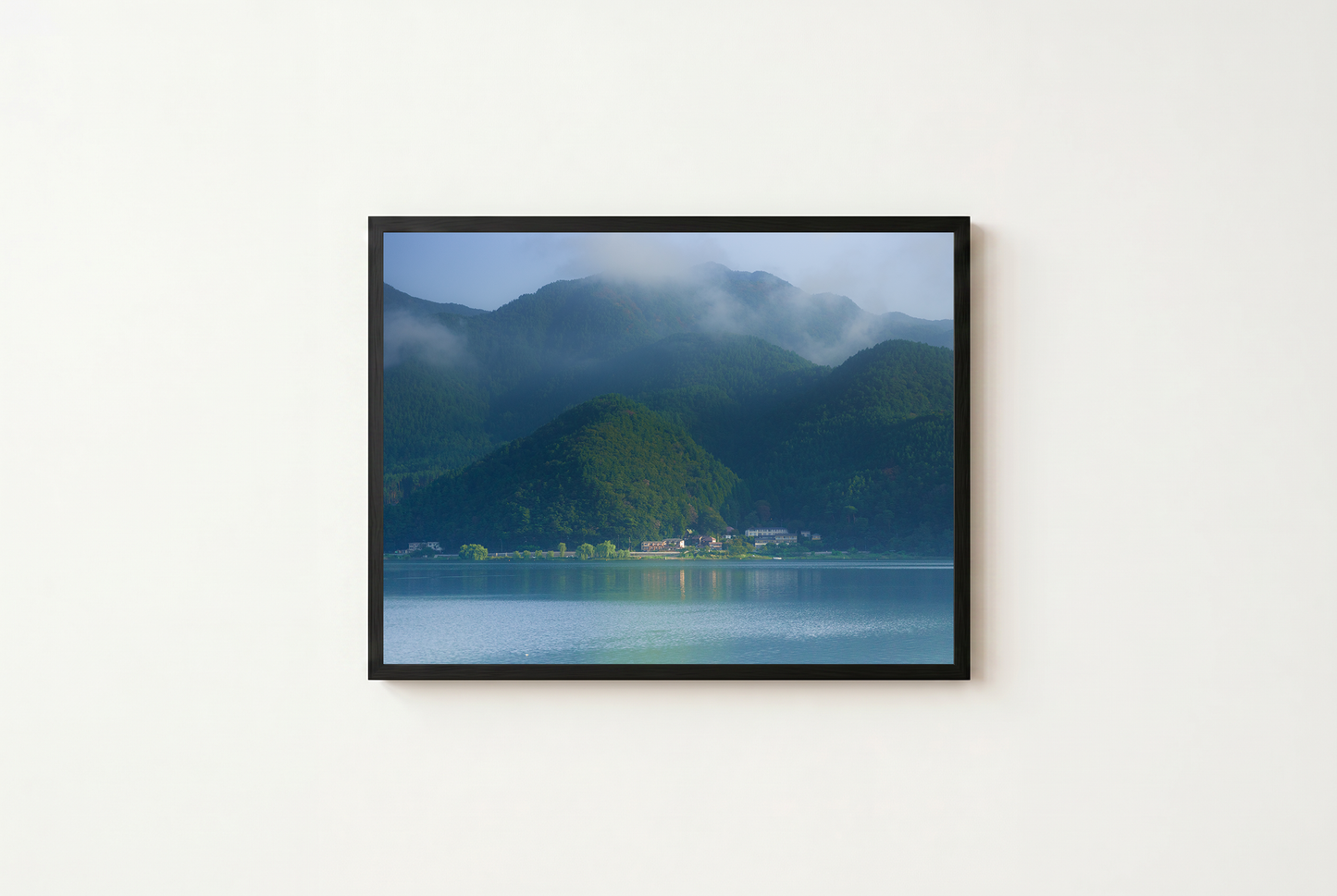Framed photograph of a mountain landscape with a lake on a white wall