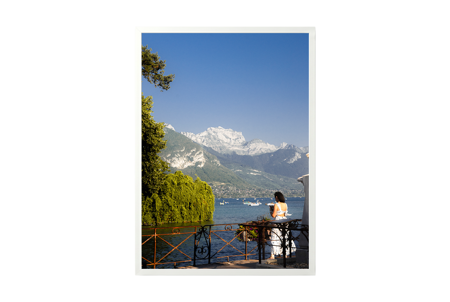 Woman in a white dress standing by a lake with mountains in the background