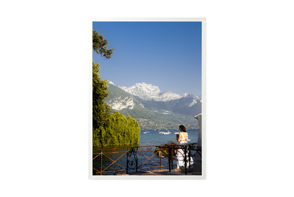 Woman in a white dress standing by a lake with mountains in the background