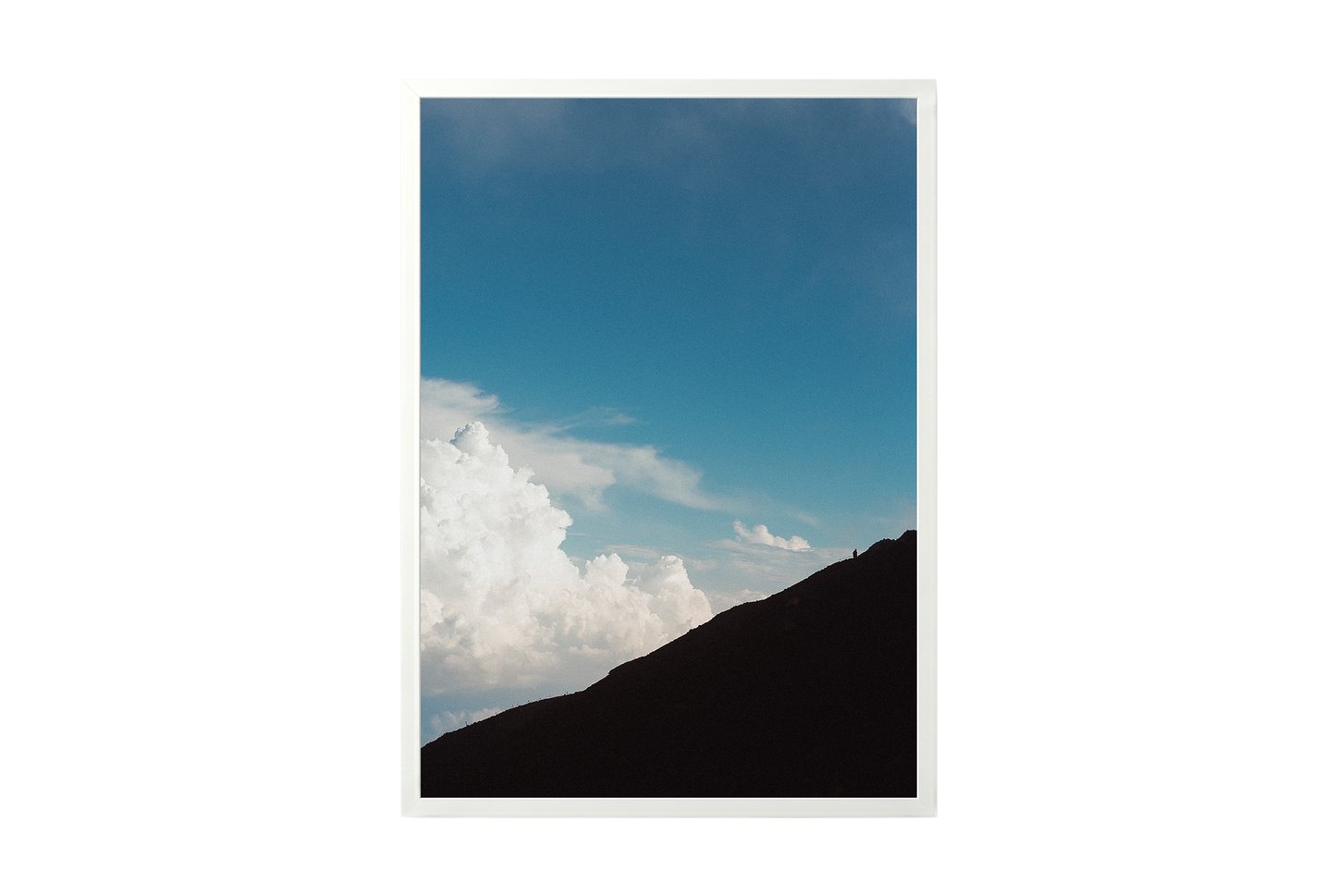 Mountain silhouette against a blue sky with clouds, framed by a white border.