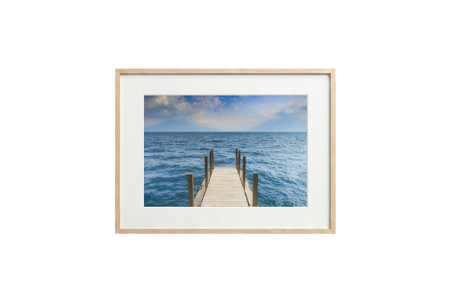 Framed photograph of a dock extending into the ocean on a white wall.