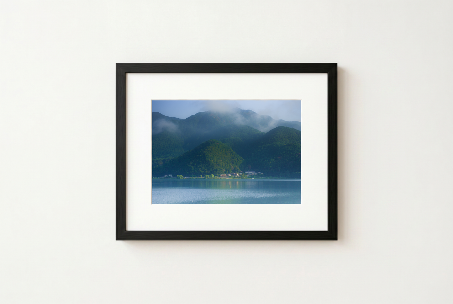 Framed photograph of a mountain landscape with a lake on a white wall