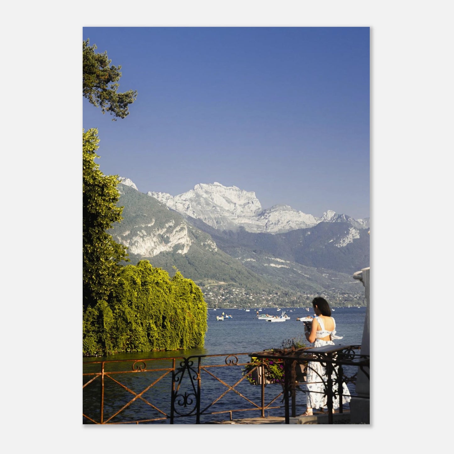 Woman sitting at a table by a lake with mountains in the background