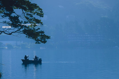 This minimalist lake photography print features a serene blue-toned landscape with a boat silhouette, making it perfect for calm wall art, Japandi decor, and modern minimalist interiors. Ideal for bedrooms, living rooms, and offices, this premium fine art print brings a peaceful, reflective atmosphere through soft blue hues and natural composition.