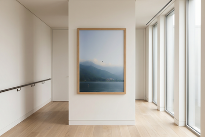 Framed artwork of a mountain landscape in a modern room with large windows.