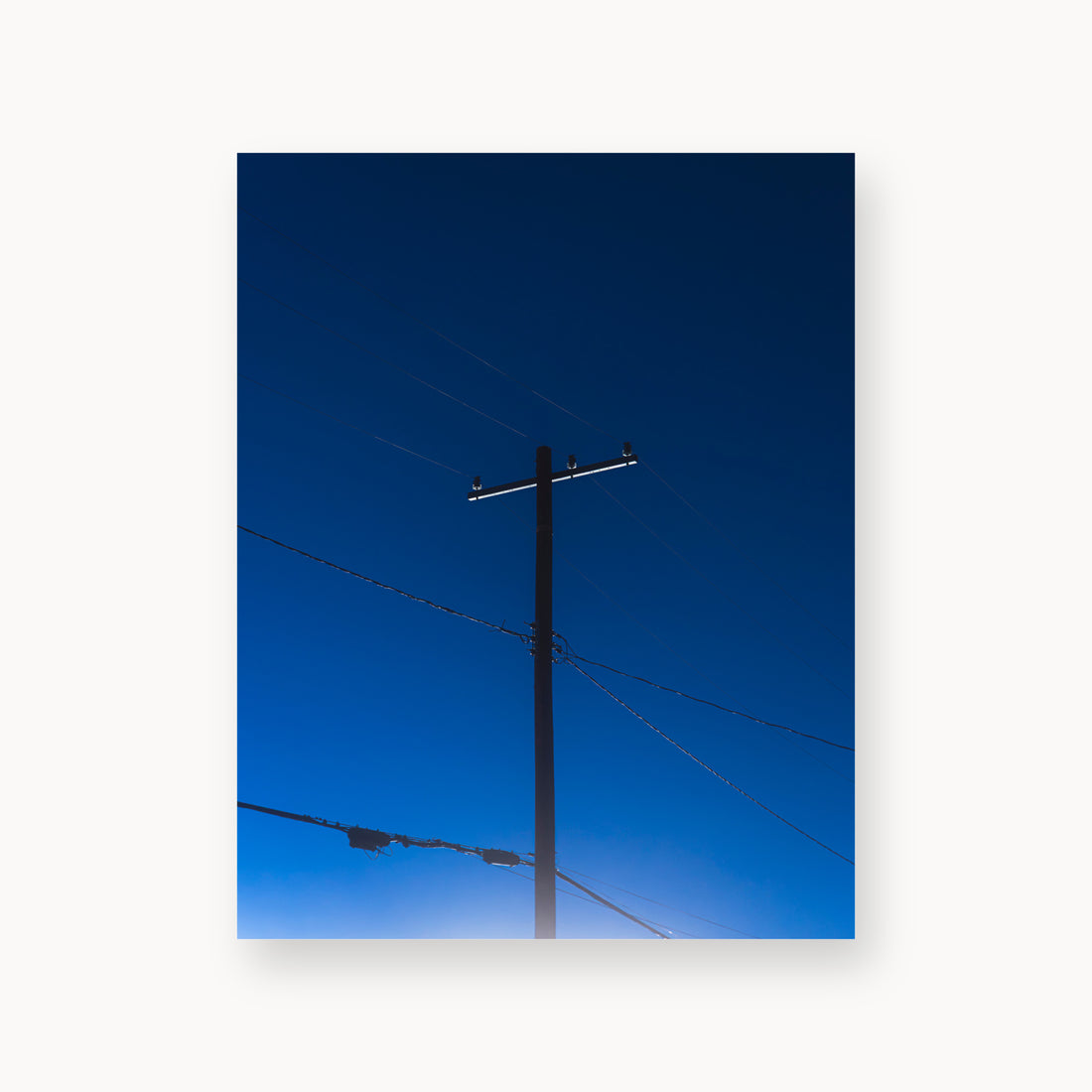 
Power — 11x14, unframed. A utility pole and crossing wires against a saturated blue evening sky.