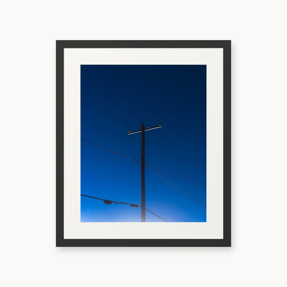 
Power — 16x20, black frame. A utility pole and crossing wires against a saturated blue evening sky.