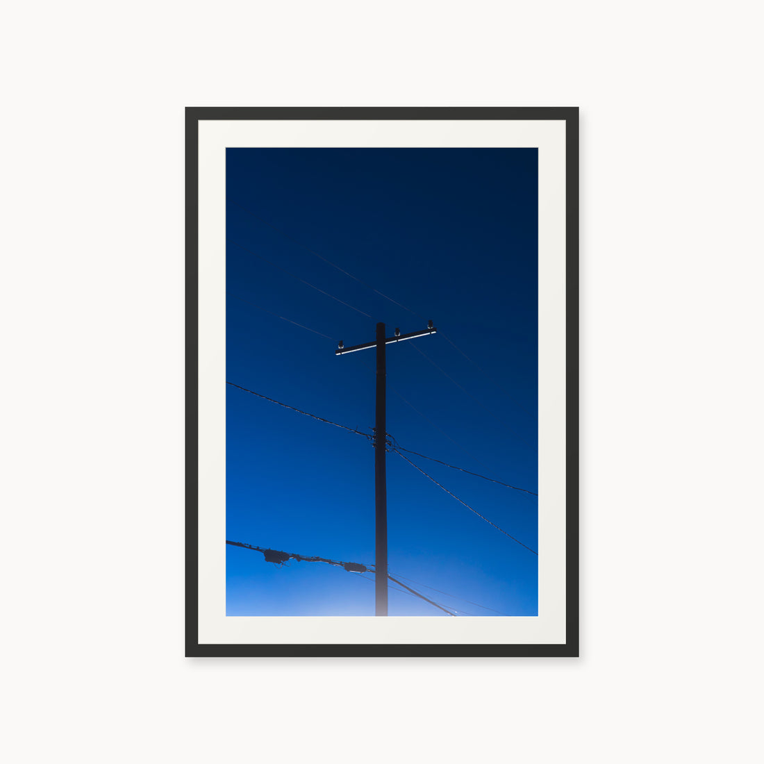 
Power — 24x36, black frame. A utility pole and crossing wires against a saturated blue evening sky.