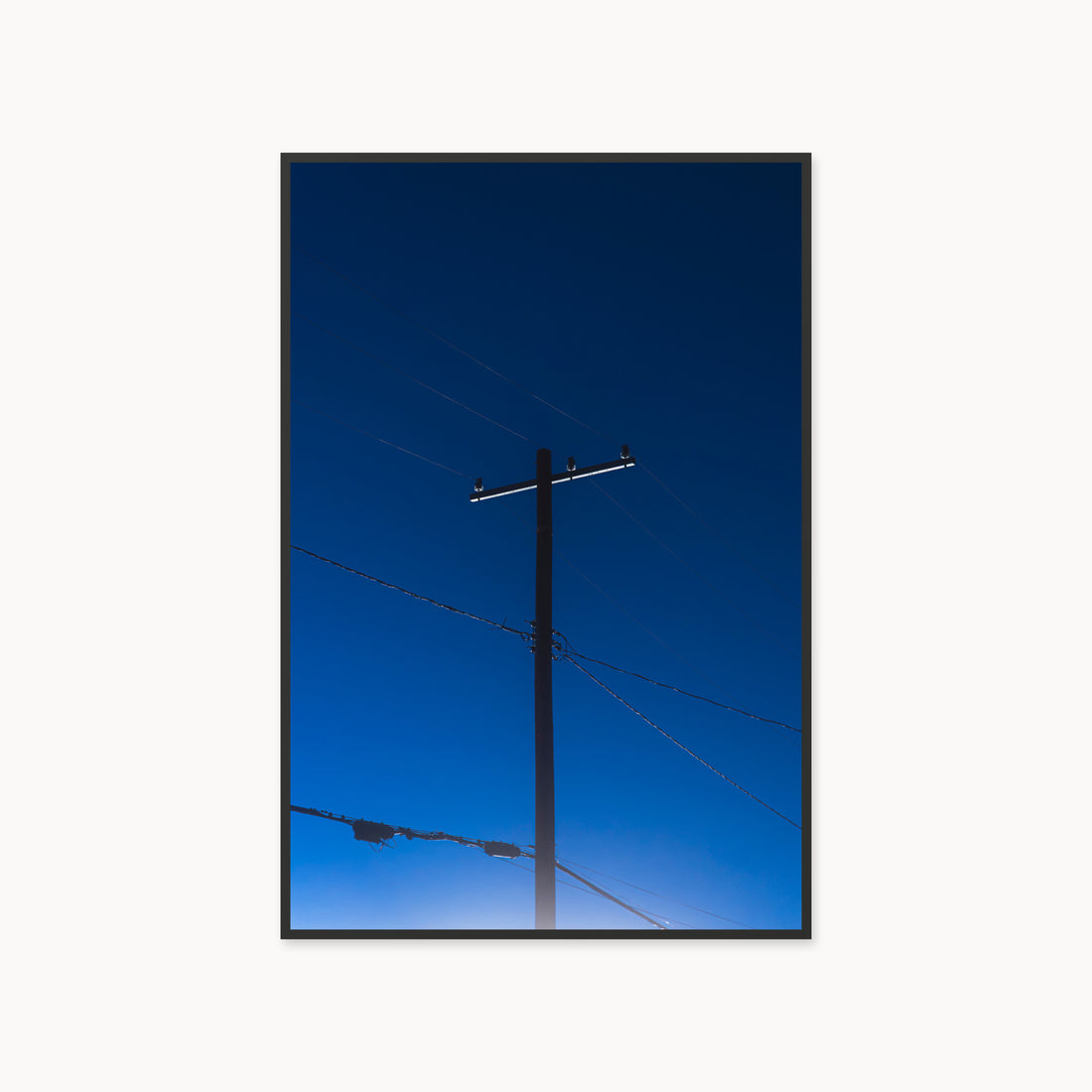 
Power — 40x60, black frame. A utility pole and crossing wires against a saturated blue evening sky.
