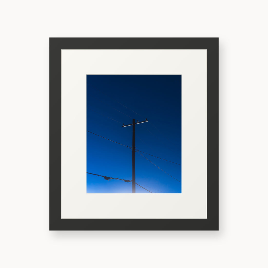 
Power — 8x10, black frame. A utility pole and crossing wires against a saturated blue evening sky.