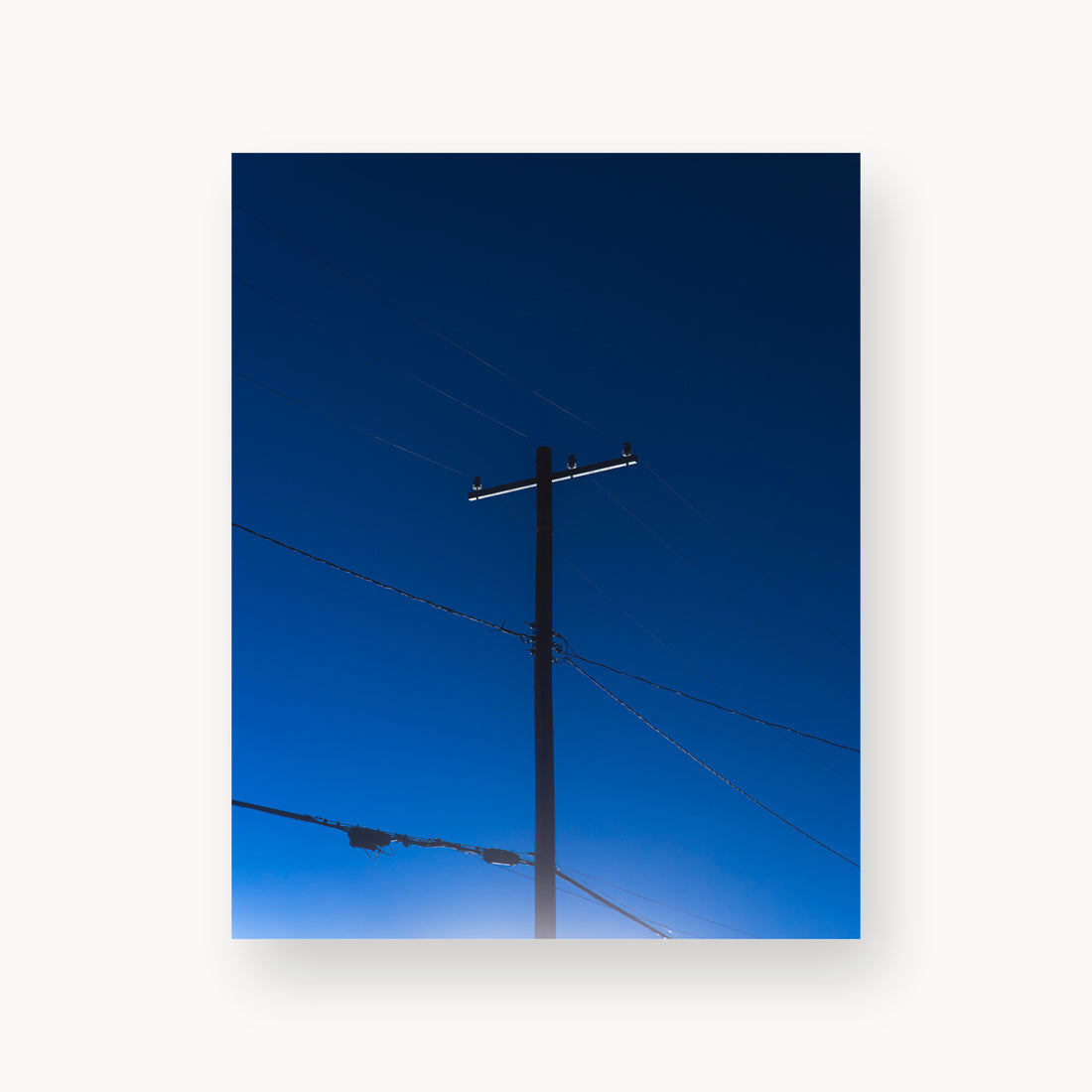 
Power — 8x10, unframed. A utility pole and crossing wires against a saturated blue evening sky.