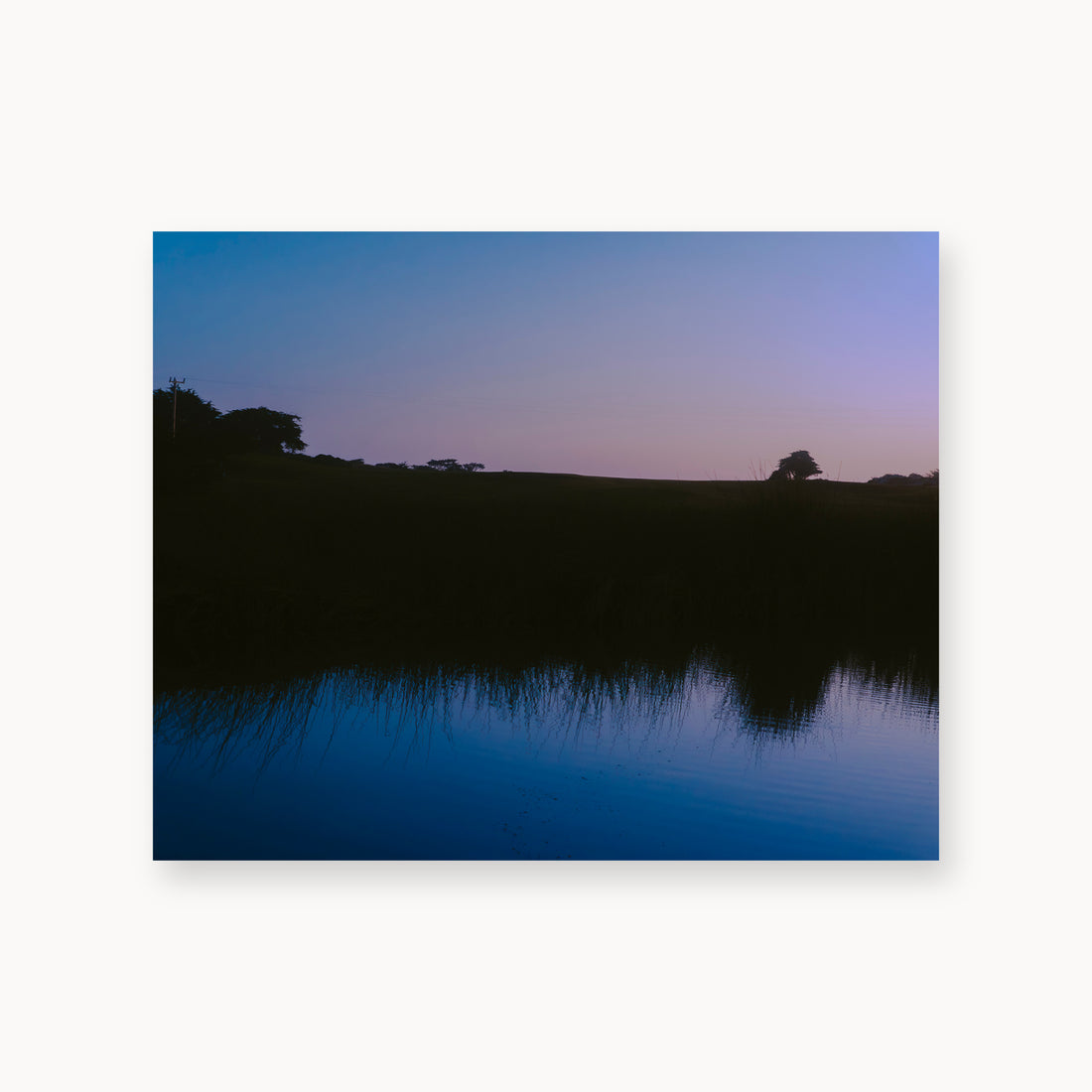
What Lays Beneath — 16x20, unframed. Dark trees and a twilight shoreline reflected across blue water.