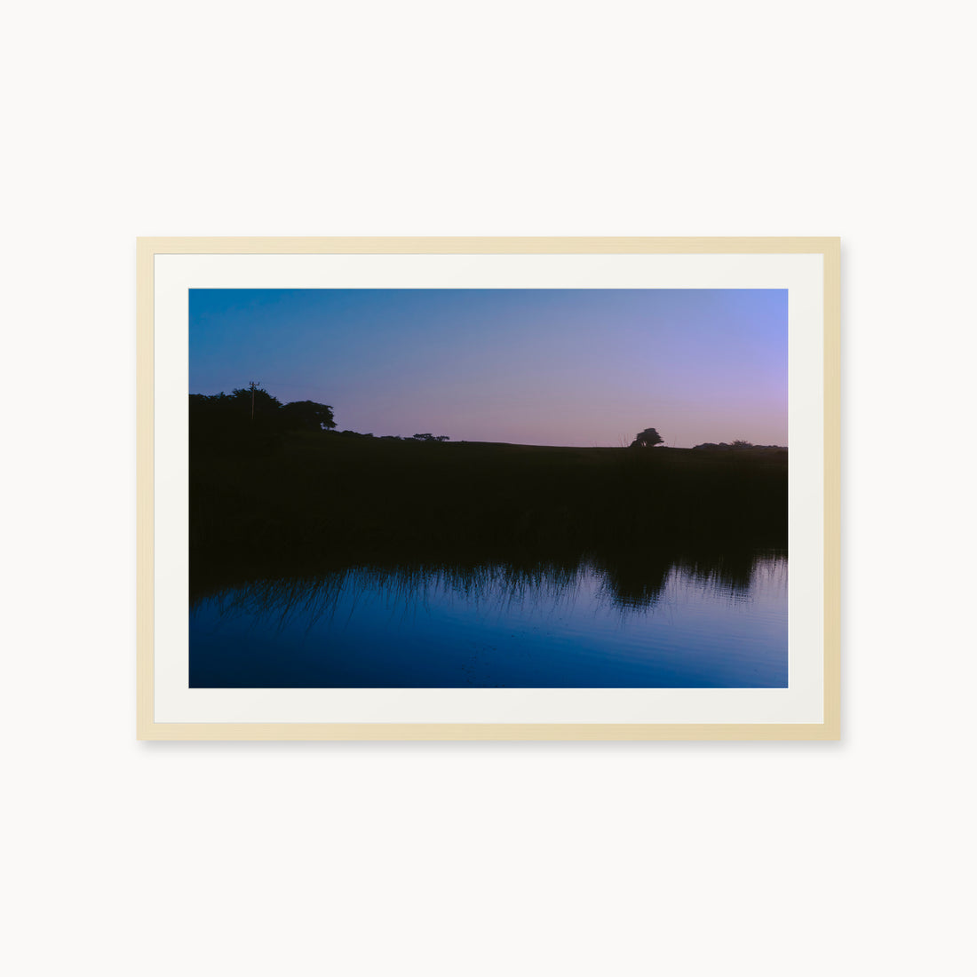 
What Lays Beneath — 24x36, maple frame. Dark trees and a twilight shoreline reflected across blue water.