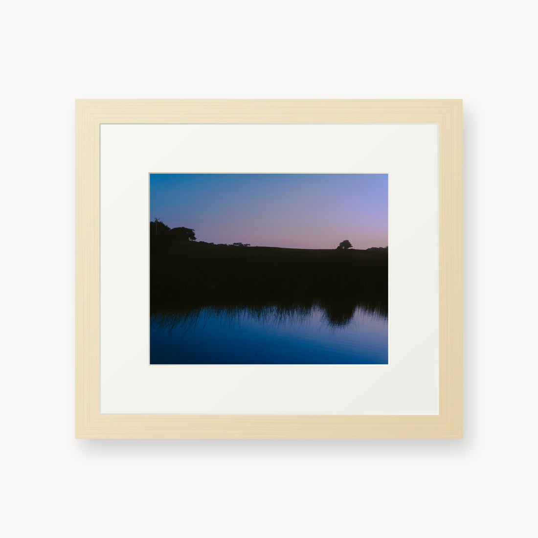 
What Lays Beneath — 8x10, maple frame. Dark trees and a twilight shoreline reflected across blue water.